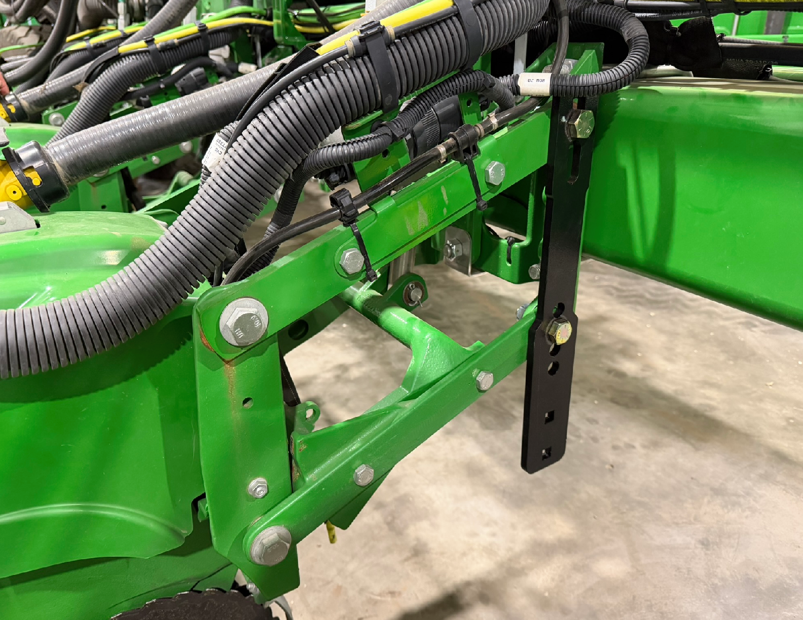Green agricultural machinery with black cables attached.