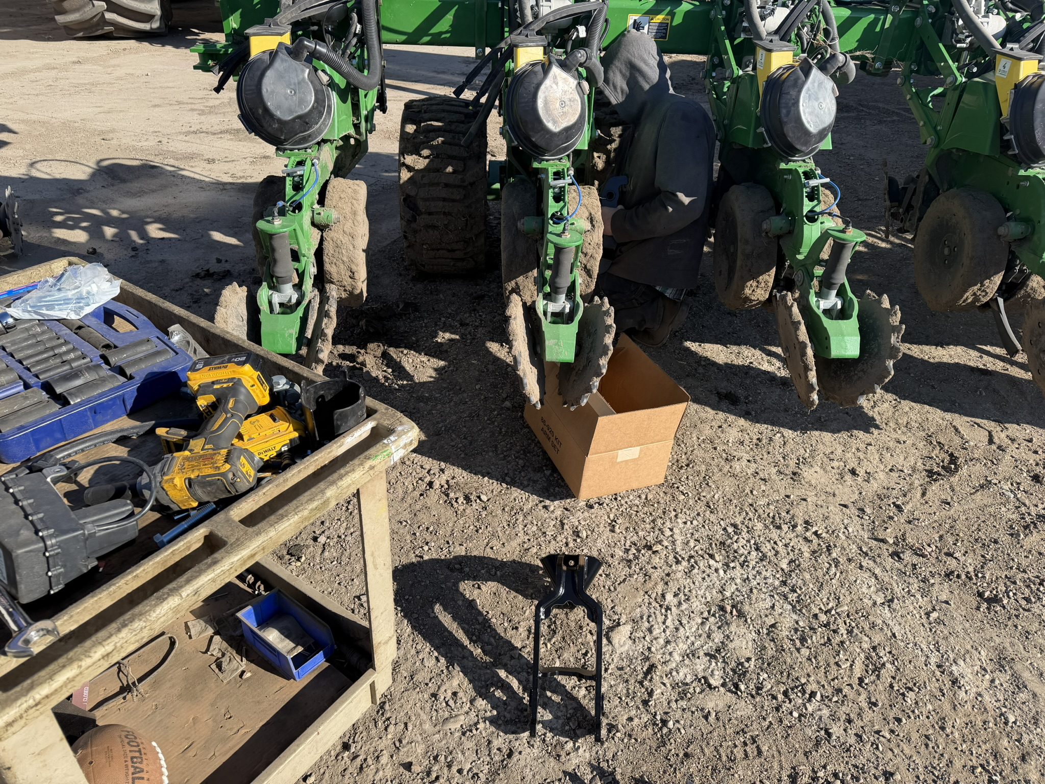 Farm machinery and tools on dirt ground.
