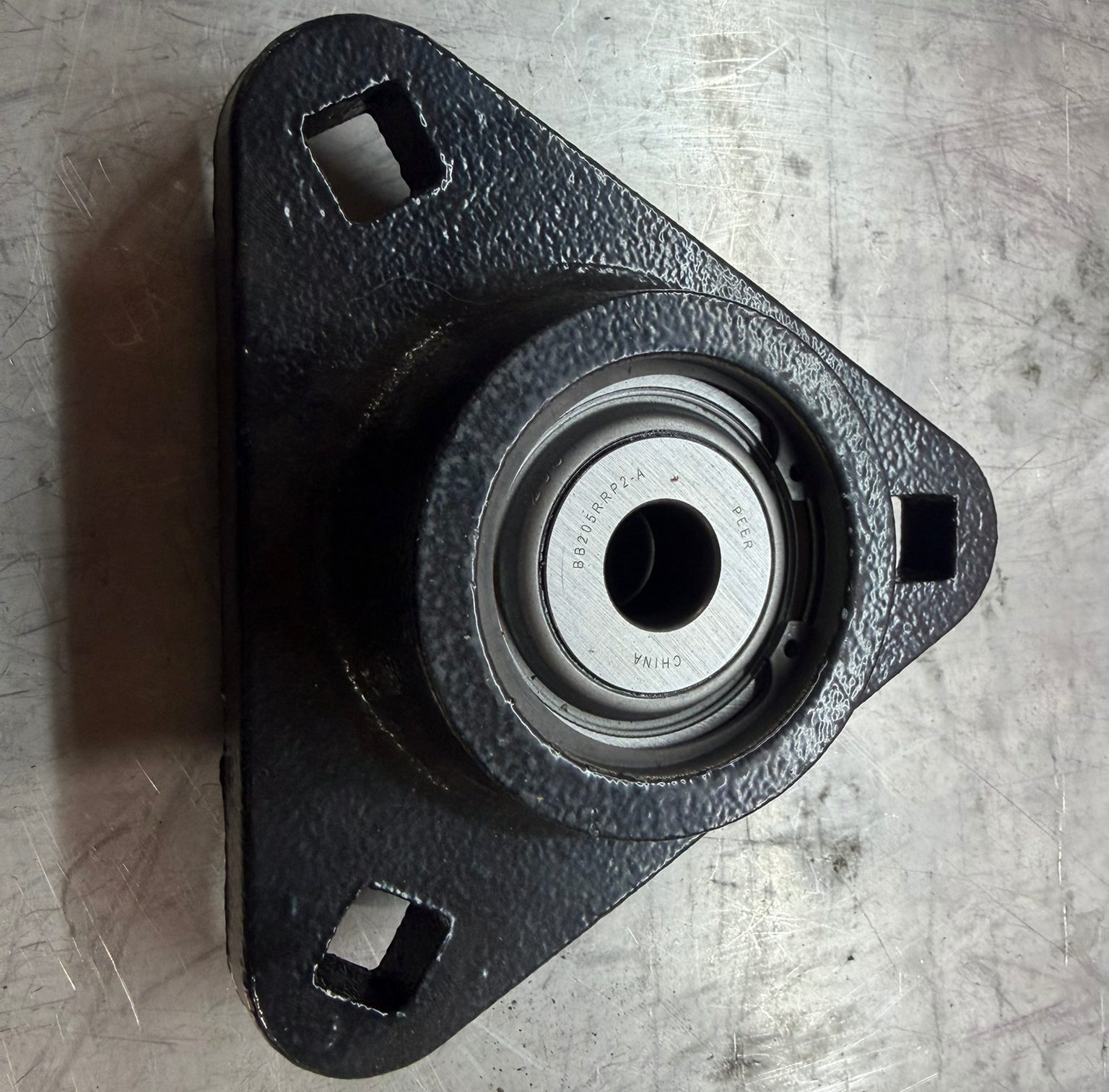 Triangular metal bearing housing on table.