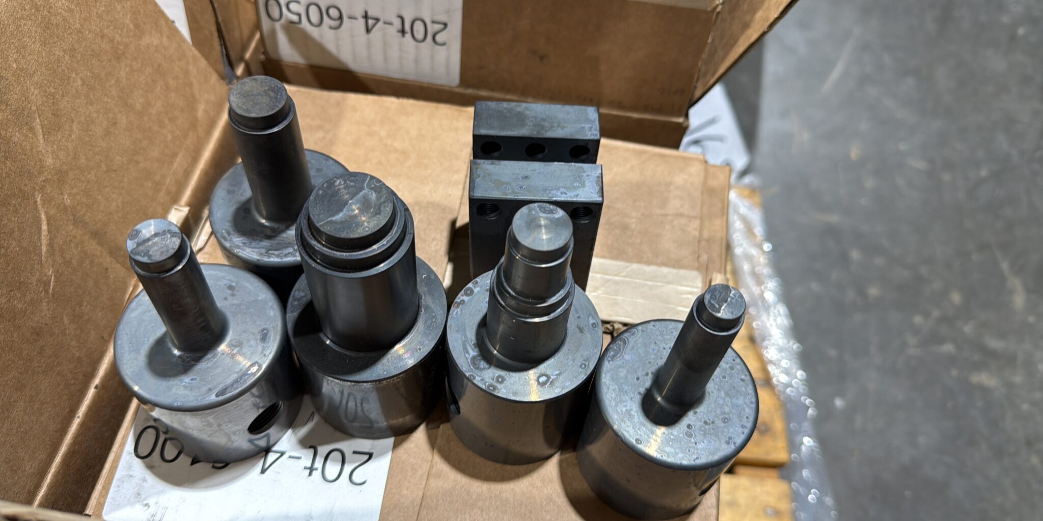 Metal cylindrical tools in a cardboard box.