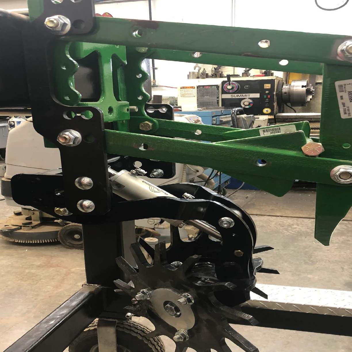 Green and black machinery in workshop setting.