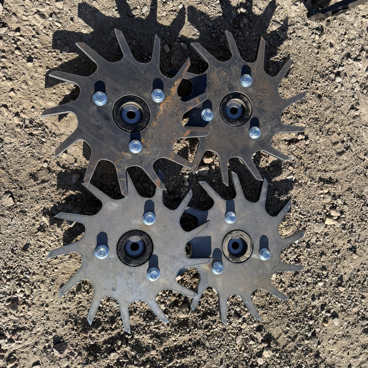 Four metal star-shaped gears on ground.