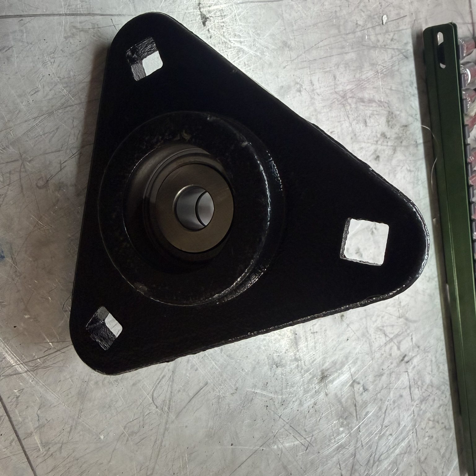 Triangular metal component on a workbench.