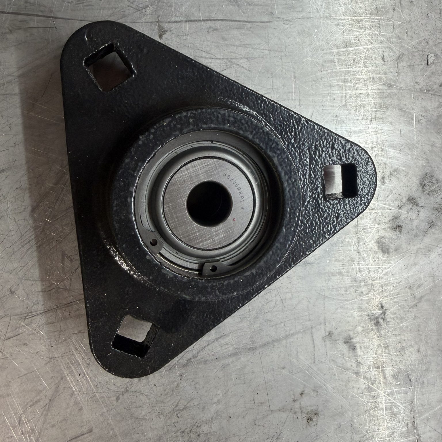 Triangular metal bearing on textured surface.